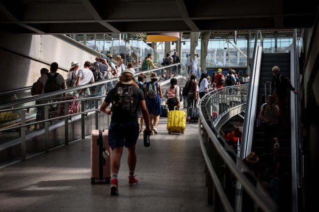 People walk with their luggages toward the platforms of the gare de Lyon train station in Paris on July 12, 2025. (Photo by Guillaume BAPTISTE / AFP)