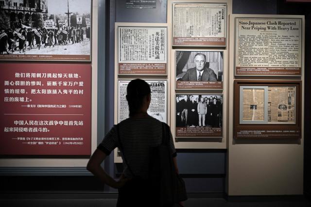 A woman reads news on newspaper about Sino-Japan's war as people visit the memorial site of the full outbreak of the Chinese People's War of Resistance Against Japanese Aggression in Beijing on July 12, 2025. China's government on July 7, marks the 80th anniversary of the end of China's War of Resistance Against Japanese Aggression. (Photo by Adek BERRY / AFP)