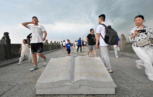 People visit the Lugou or Marco Polo bridge adjacent to the memorial site of the full outbreak of the Chinese People's War of Resistance Against Japanese Aggression in Beijing on July 12, 2025. China's government on July 7, marks the 80th anniversary of the end of China's War of Resistance Against Japanese Aggression. (Photo by Adek BERRY / AFP)