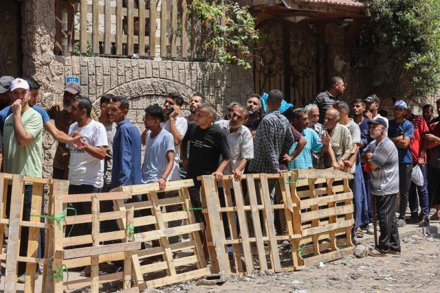Palestinians line up to receive bags of flour at a UN World Food Programme (WFP) warehouse on Al-Jalaa street in Gaza City, in the central Gaza Strip on July 12, 2025. Indirect talks between Hamas and Israel for a ceasefire in Gaza are being held up by Israel's proposals to keep troops in the territory, two Palestinian sources with knowledge of the discussions told AFP on July 12. (Photo by Omar AL-QATTAA / AFP)