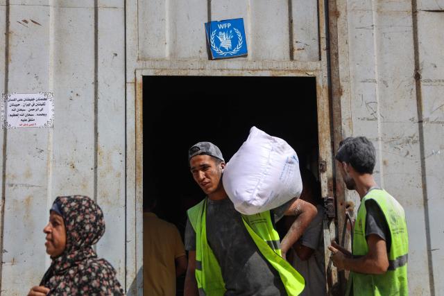 A Palestinian man carries a bag of flour at a UN World Food Programme (WFP) warehouse on Al-Jalaa street in Gaza City, in the central Gaza Strip on July 12, 2025. Indirect talks between Hamas and Israel for a ceasefire in Gaza are being held up by Israel's proposals to keep troops in the territory, two Palestinian sources with knowledge of the discussions told AFP on July 12. (Photo by Omar AL-QATTAA / AFP)