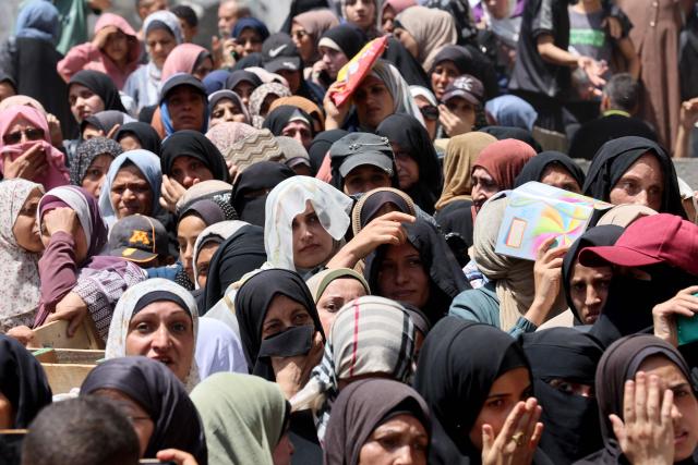 Palestinian women line up to receive bags of flower at a UN World Food Programme (WFP) warehouse on Al-Jalaa street in Gaza City, in the central Gaza Strip on July 12, 2025. Indirect talks between Hamas and Israel for a ceasefire in Gaza are being held up by Israel's proposals to keep troops in the territory, two Palestinian sources with knowledge of the discussions told AFP on July 12. (Photo by Omar AL-QATTAA / AFP)