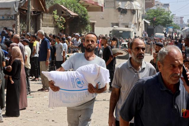A Palestinian man carries a bag of flower at a UN World Food Programme (WFP) warehouse on Al-Jalaa street in Gaza City, in the central Gaza Strip on July 12, 2025. Indirect talks between Hamas and Israel for a ceasefire in Gaza are being held up by Israel's proposals to keep troops in the territory, two Palestinian sources with knowledge of the discussions told AFP on July 12. (Photo by Omar AL-QATTAA / AFP)