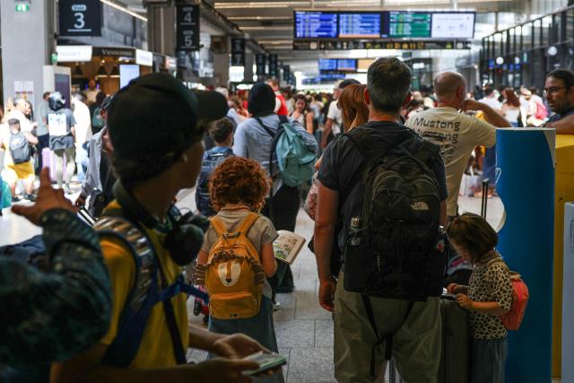 Travellers wait for their trains at the Montparnasse train station, in Paris on July 12, 2025, at the start of the busiest weekend of the French summer holidays. (Photo by ALAIN JOCARD / AFP)