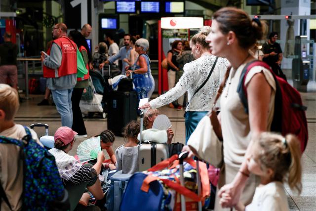 Travellers wait for their trains at the Montparnasse train station, in Paris on July 12, 2025, at the start of the busiest weekend of the French summer holidays. (Photo by ALAIN JOCARD / AFP)