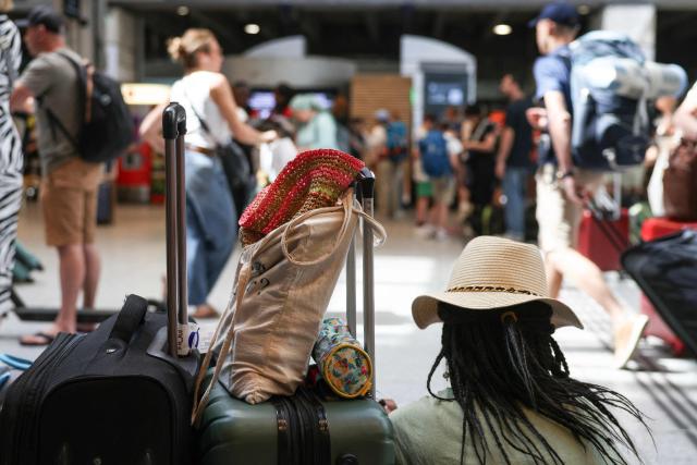 Travellers wait for their trains at the Montparnasse train station, in Paris on July 12, 2025, at the start of the busiest weekend of the French summer holidays. (Photo by ALAIN JOCARD / AFP)