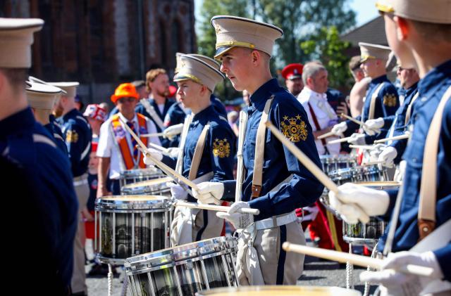 A band joins members of Orange Order as they take part in a parade in Belfast on July 12, 2025, to celebrate the battle of the Boyne in 1690, when the Protestant King William of Orange defeated the Catholic King James. (Photo by PAUL FAITH / AFP)