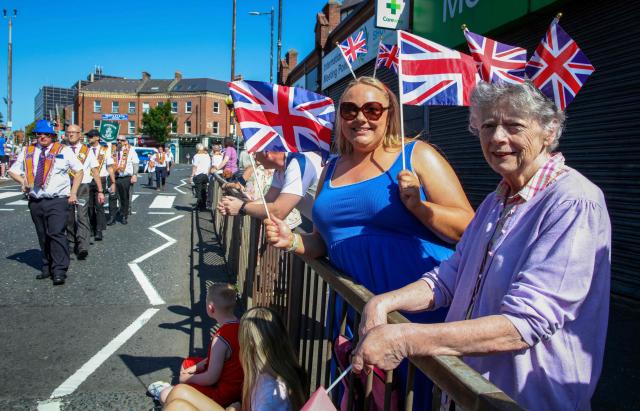 Spectators watch on as members of Orange Order take part in a parade in Belfast on July 12, 2025, to celebrate the battle of the Boyne in 1690, when the Protestant King William of Orange defeated the Catholic King James. (Photo by PAUL FAITH / AFP)