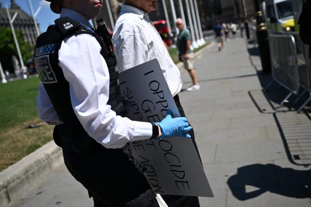 A Police officer confiscates a placard as protesters gather in support of the pro-palestinian group "Palestine Action", in Parliament Square, London on July 12, 2025, following the Home Secretary's decision to proscribe the group under anti-terror laws. Police have warned that expressing support for Palestine Action would be a criminal offence after the ban kicked in last weekend. (Photo by JUSTIN TALLIS / AFP)