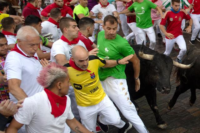 Participants run ahead of La Palmosilla breed bulls during the seventh running of the bulls of the San Fermin festival in Pamplona, northern Spain, on July 13, 2025. Thousands of people every year attend the week-long festival and its famous "encierros" or bull runs, every day at 8:00 a.m. through the narrow streets of the old town over an 850 meters (yard) course while runners ahead of them try to stay close to the bulls without falling over or being gored. (Photo by JORGE GUERRERO / AFP)