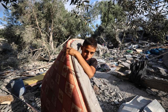 TOPSHOT - A Palestinian boy salvages a mattress from the rubble of a house in the aftermath of an overnight Israeli strike that hit Nuseirat in the central Gaza Strip on July 13, 2025. (Photo by Eyad BABA / AFP)
