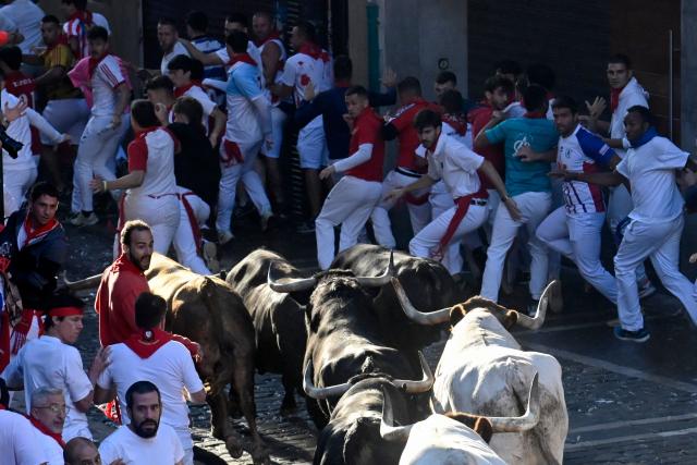 Participants run ahead of La Palmosilla breed bulls during the seventh running of the bulls of the San Fermin festival in Pamplona, northern Spain, on July 13, 2025. Thousands of people every year attend the week-long festival and its famous "encierros" or bull runs, every day at 8:00 a.m. through the narrow streets of the old town over an 850 meters (yard) course while runners ahead of them try to stay close to the bulls without falling over or being gored. (Photo by MIGUEL RIOPA / AFP)