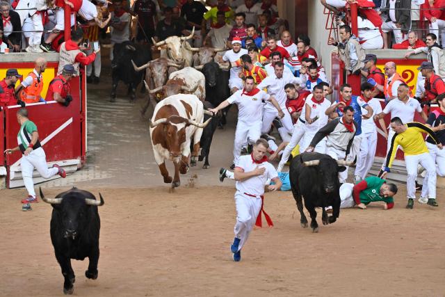 Some participants fall down as the bulls from La Palmosilla ranch enter the bullring during the seventh running of the bulls of the San Fermin festival in Pamplona, northern Spain, on July 13, 2025. Thousands of people every year attend the week-long festival and its famous "encierros" or bull runs, every day at 8:00 a.m. through the narrow streets of the old town over an 850 meters (yard) course while runners ahead of them try to stay close to the bulls without falling over or being gored. (Photo by ANDER GILLENEA / AFP)