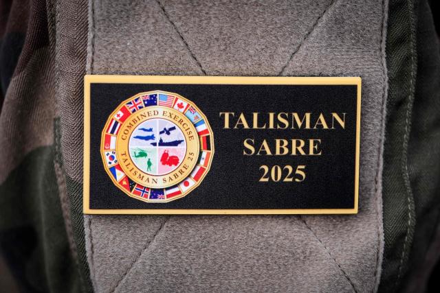 A member of the French defence forces wears a badge displaying the emblem of the annual Talisman Sabre exercise, as they stand aboard the French patrol vessel Auguste Benebig, in Sydney on July 13, 2025. More than 30,000 military personnel from 19 nations are set to join in the annual Talisman Sabre exercise from Sunday across Australia and Papua New Guinea. (Photo by DAVID GRAY / AFP)
