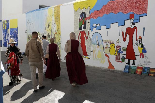 Visitors walk near mural paintings during the annual Asilah Arts Festival, which transforms the coastal Moroccan town into an open air art gallery, on July 12, 2025. (Photo by Abdel Majid BZIOUAT / AFP)