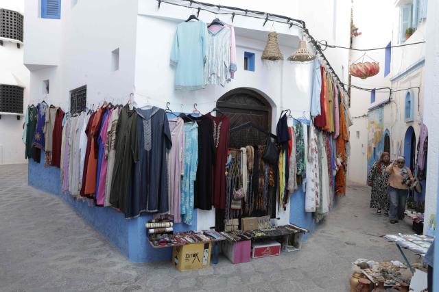 People walk near a shop during the annual Asilah Arts Festival, which transforms the coastal Moroccan town into an open air art gallery, on July 12, 2025. (Photo by Abdel Majid BZIOUAT / AFP)