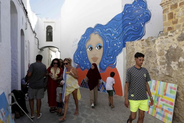 People visit the annual Asilah Arts Festival, which transforms the coastal Moroccan town into an open air art gallery, on July 12, 2025. (Photo by Abdel Majid BZIOUAT / AFP)