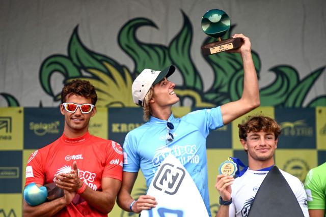 France's surfer Sam Piter (2nd L) celebrates next to second placed France's Tiago Carrique (L) after winning the final of the Lacanau Pro World Surf League (WSL) event along the Atlantic Ocean in Lacanau, south-western France on July 13, 2025. For nearly fifty years, the Lacanau Pro has withstood all the upheavals in the surf industry to become the last major international gathering in mainland France. (Photo by Christophe ARCHAMBAULT / AFP)