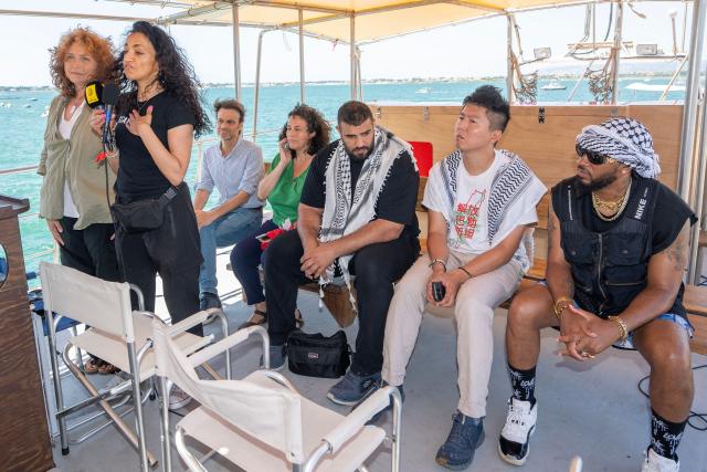 US lawyer and co-founder the International Solidarity Movement (ISM) Huwaida Arraf (2ndL)  addresses a press conference next to other crew members the Freedom Flotilla ship "Handala" ahead of the boat's departure for Gaza at a port in Syracuse, Sicily, southern Italy, on July 13, 2025. A Gaza-bound boat carrying pro-Palestinian activists and humanitarian aid left Sicily on July 13, 2025, over a month after Israel detained and deported people aboard a previous vessel, carrying about fifteen activists. (Photo by Giovanni ISOLINO / AFP)