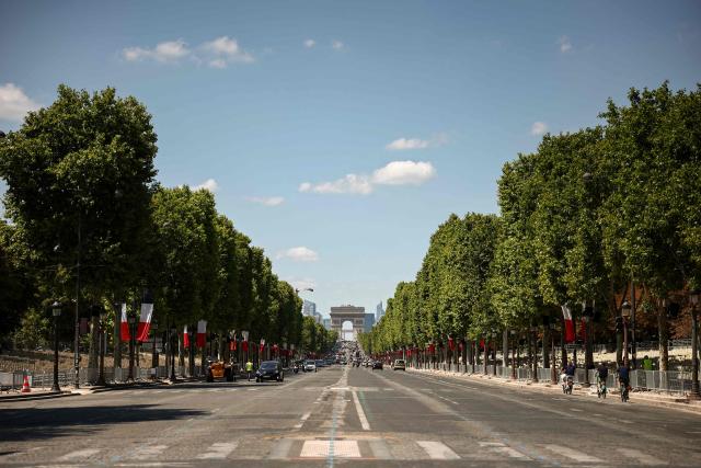 This photograph shows the Champs-Elysees Avenue with its trees decorated with French national flags in Paris on July 13, 2025, on the eve of the traditional annual Bastille day military parade. (Photo by Guillaume BAPTISTE / AFP)