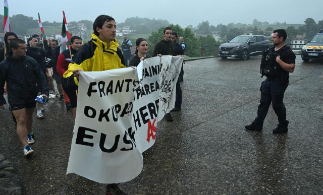 Young Basque independence supporters hold a banner reading "against the French and Spanish occupation let us liberate the Basque country" during a demonstration against the celebration of July 14 in the Basque Country, called by the U14 collective (Uztailak 14-14 Juillet) in Espelette, southwestern France, on July 14, 2025. (Photo by Gaizka IROZ / AFP)