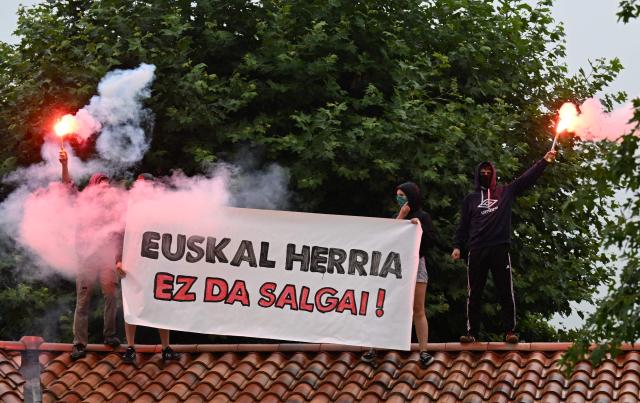 Young Basque independence supporters on a roof hold a banner reading "the basque county is not for sale" during a demonstration against the celebration of July 14 in the Basque Country, called by the U14 collective (Uztailak 14-14 Juillet) in Espelette, southwestern France, on July 14, 2025. (Photo by Gaizka IROZ / AFP)