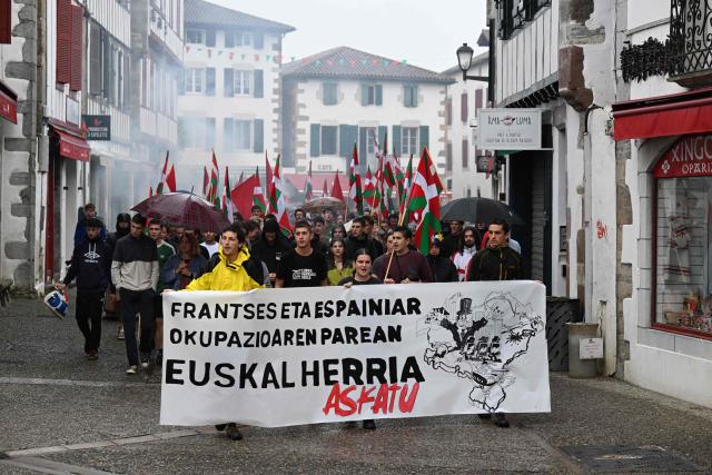 Young Basque independence supporters hold a banner reading "against the French and Spanish occupation let us liberate the Basque country" during a demonstration against the celebration of July 14 in the Basque Country, called by the U14 collective (Uztailak 14-14 Juillet) in Espelette, southwestern France, on July 14, 2025. (Photo by Gaizka IROZ / AFP)