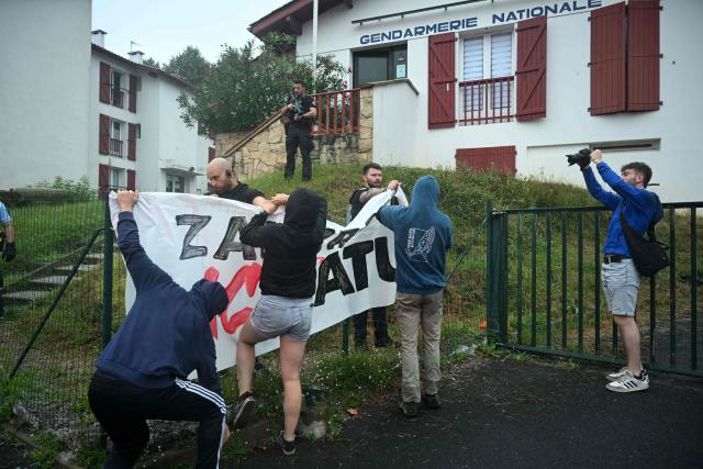 Young Basque independence supporters hang a banner near a police station during a demonstration against the celebration of July 14 in the Basque Country, called by the U14 collective (Uztailak 14-14 Juillet) in Espelette, southwestern France, on July 14, 2025. (Photo by Gaizka IROZ / AFP)