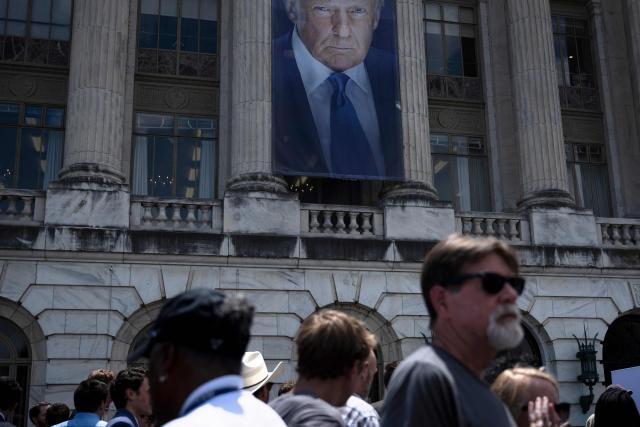 An image of US President Donald Trump hangs outside the USDA headquarters building as people attend a free ice cream event following a news conference with US Secretary of Health and Human Services in Washington, DC, on July 14, 2025. According to US media reports, ice cream makers in the US are planning to eliminate several artificial colors from their products by 2028. The announcement comes less than a week before National Ice Cream Day on July 20. (Photo by Brendan Smialowski / AFP)