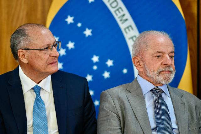 Brazil's President Luiz Inacio Lula da Silva (R) looks on next to his Minister of Industry and Trade, Geraldo Alckmin, during the launch of a program to support taxi drivers at Planalto Palace in Brasilia on July 14, 2025. Luis Inácio Lula da Silva instructed his vice president and minister of industry and trade, Geraldo Alckmin, to form a commission with the sectors most affected by the 50% tariffs imposed by US President Donald Trump to negotiate with the US government in an attempt to prevent the tariffs from coming into effect on August 1. (Photo by EVARISTO SA / AFP)