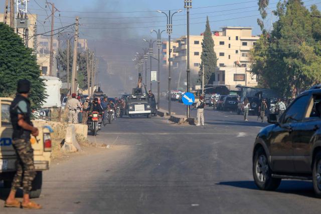Members of Syria's security forces look on as smoke billows during clashes between Bedouin tribes and Druze fighers in an area between Mazraa and Walga near the predominantly Druze city of Sweida on July 14, 2025. Israeli Defence Minister Israel Katz issued a warning to Damascus on July 14 after the military struck several tanks in southern Syria to prevent them from reaching a Druze village near the scene of sectarian clashes. (Photo by Bakr ALKASEM / AFP)