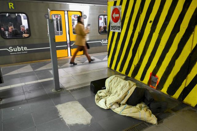 A man sleeps on the floor of a subway station in Buenos Aires on July 14, 2025. (Photo by Luis ROBAYO / AFP)
