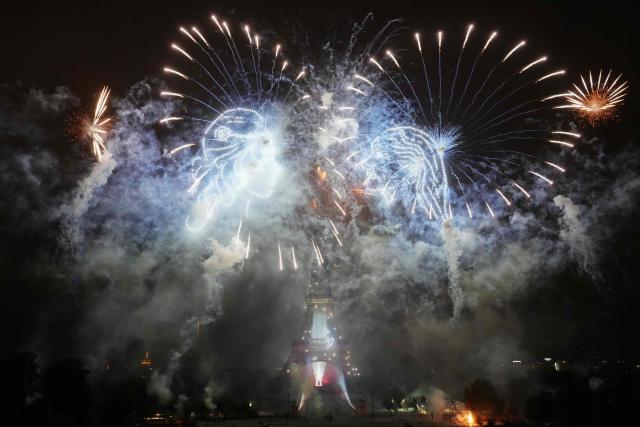Fireworks explode around the Eiffel Tower as drones form two faces in profile during a choreographed light show to celebrate Bastille Day, in Paris, on July 14, 2025. (Photo by Dimitar DILKOFF / AFP)