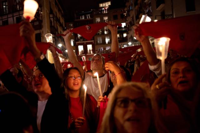 Revellers raise red scarves and candles as they sing the song "Pobre de Mi", marking the end of the San Fermin festival in Pamplona, Spain on July 14, 2025. Thousands of people attend the week-long festival and its famous "encierros" or bull runs. Every day at 8:00 a.m., bulls are released through the narrow streets of the old town over an 850-meter course while runners ahead of them try to stay close without falling over or being gored. (Photo by Jorge GUERRERO / AFP)