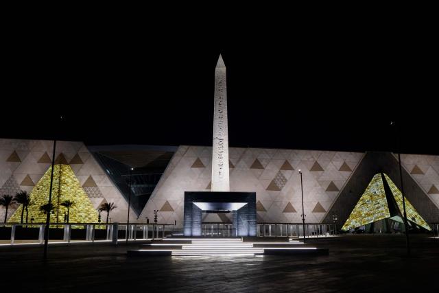 (FILES) The Obelisk of Ramses II is pictured before the facade and entrance of the new Grand Egyptian Museum in Giza near Cairo late on April 6, 2025. The museum was expected to attract up to five million visitors annually, fuelling optimism across Cairo's battered tourism sector. But less than three weeks before its July 3 opening, the government announced another delay, this time pushing the landmark event to the final quarter of the year. (Photo by Ludovic MARIN / POOL / AFP)