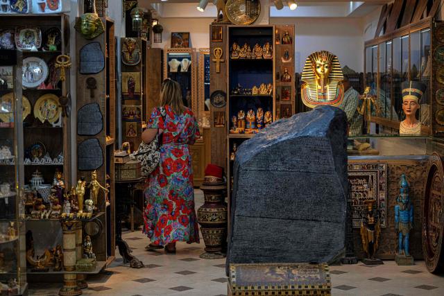 (FILES) A tourist visits Philae Jewellery Bazaar shop near the Great Pyramids plateau in Giza, south of Cairo, on June 10, 2025. The museum was expected to attract up to five million visitors annually, fuelling optimism across Cairo's battered tourism sector. But less than three weeks before its July 3 opening, the government announced another delay, this time pushing the landmark event to the final quarter of the year. (Photo by Khaled DESOUKI / AFP)