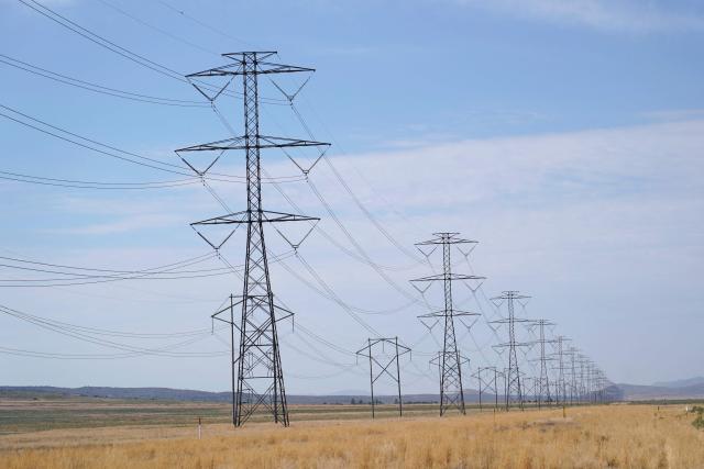 (FILES) Large electrical transmission lines run through grass lands to power the newly completed Metas Facebook data center in Eagle Mountain, Utah on July 18, 2024. In a scramble to quickly bring more data centers online, US cloud computing giants are now getting directly involved in energy production. And while they are using some renewable energy options and trying to revive nuclear power, they are also turning to fossil fuels like gas, which in the United States is relatively cheap. A fight in Davis, in the woods of rural West Virginia, is the latest example of the war between the US tech sector -- and its rapidly rising need for energy to power the AI boom -- and the communities it affects. (Photo by GEORGE FREY / AFP)