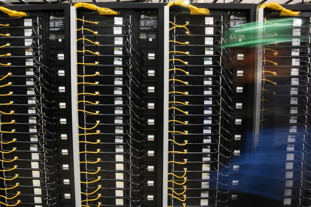 (FILES) A worker walks past crypto mining racks at a plant in Hernandarias, 350km east of Asuncion, Paraguay on August 2, 2024. In a scramble to quickly bring more data centers online, US cloud computing giants are now getting directly involved in energy production. And while they are using some renewable energy options and trying to revive nuclear power, they are also turning to fossil fuels like gas, which in the United States is relatively cheap. A fight in Davis, in the woods of rural West Virginia, is the latest example of the war between the US tech sector -- and its rapidly rising need for energy to power the AI boom -- and the communities it affects. (Photo by DANIEL DUARTE / AFP)