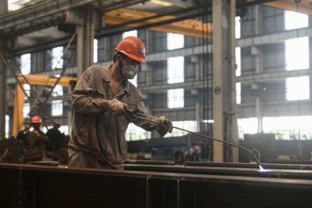 An employee works at a factory which produces steel structures in Hangzhou, in China’s eastern Zhejiang province on July 15, 2025. China's economy grew by 5.2 percent in the second quarter of the year, official data showed on July 15, matching forecasts as strong exports helped it withstand trade war pressures. (Photo by AFP) / China OUT