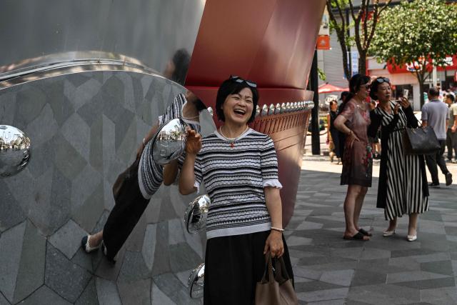 People pose for pictures next to "The Louis", a large ship-shaped structure of the Louis Vuitton brand, in Shanghai on June 15, 2025. (Photo by Hector RETAMAL / AFP)