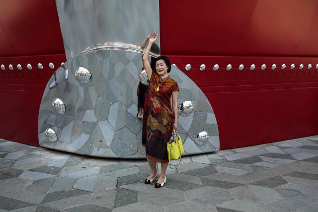 A woman poses for a picture next to "The Louis", a large ship-shaped structure of the Louis Vuitton brand, in Shanghai on July 15, 2025. (Photo by Hector RETAMAL / AFP)