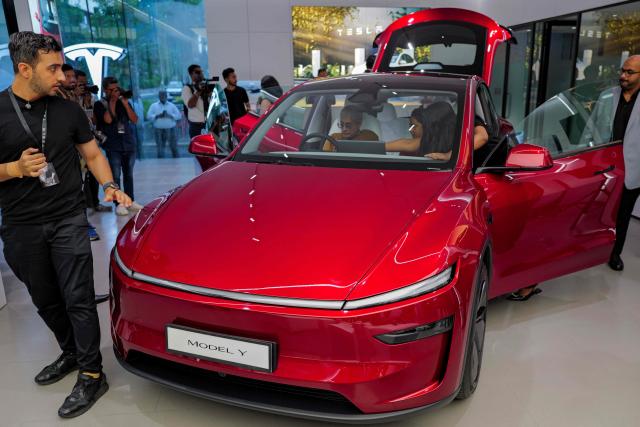 Media personnel inspect Tesla's 'Model Y' vehicle during the inauguration of India's first Tesla showroom, in Mumbai on July 15, 2025. Tesla unveiled its first showroom in India on July 15, marking its entry into the world's most populous country, as Elon Musk's electric vehicle company seeks new customers amid sagging sales in the United States and Europe. (Photo by Punit PARANJPE / AFP)