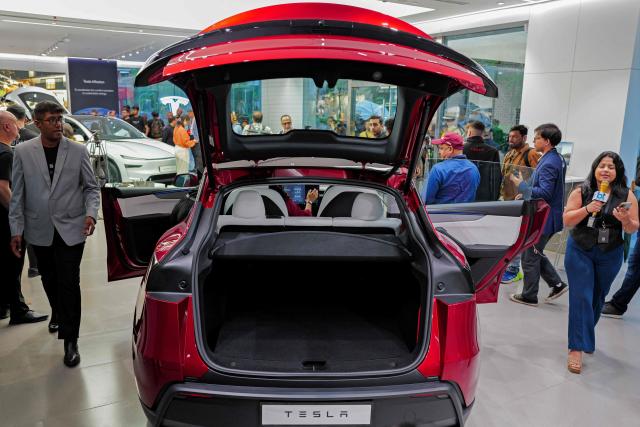 Media personnel inspect Tesla's 'Model Y' vehicle during the inauguration of India's first Tesla showroom, in Mumbai on July 15, 2025. Tesla unveiled its first showroom in India on July 15, marking its entry into the world's most populous country, as Elon Musk's electric vehicle company seeks new customers amid sagging sales in the United States and Europe. (Photo by Punit PARANJPE / AFP)
