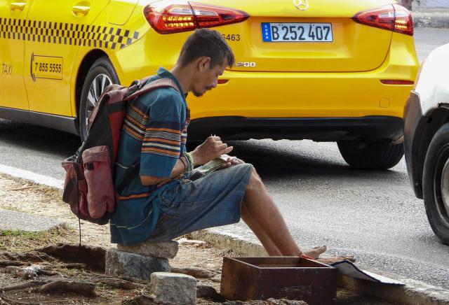 A beggar counts money he collected from car drivers in Havana, on July 15, 2025. Begging in Cuba is associated with extreme poverty, family neglect, and mental health issues, and although the authorities minimize the phenomenon, citizens demand that it be recognized in order to address it. (Photo by ADALBERTO ROQUE / AFP)