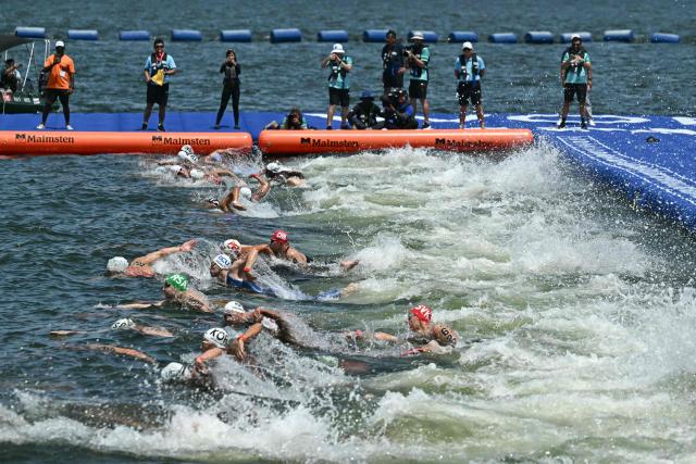 Swimmers dive into the water at the start of the men's 10km open water swimming event during the 2025 World Aquatics Championships at Sentosa Island in Singapore on July 16, 2025. (Photo by Manan VATSYAYANA / AFP)