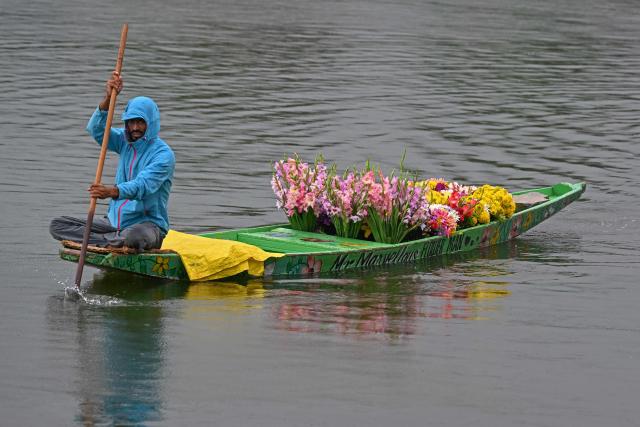 A flower vendor paddles his boat amid rainfall in Srinagar on July 16, 2025. (Photo by Tauseef MUSTAFA / AFP)