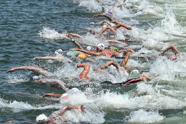 Swimmers dive into the water at the start of the men's 10km open water swimming event during the 2025 World Aquatics Championships at Sentosa Island in Singapore on July 16, 2025. (Photo by Manan VATSYAYANA / AFP)