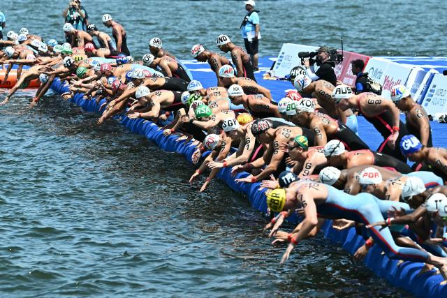 Swimmers dive into the water at the start of the men's 10km open water swimming event during the 2025 World Aquatics Championships at Sentosa Island in Singapore on July 16, 2025. (Photo by Manan VATSYAYANA / AFP)