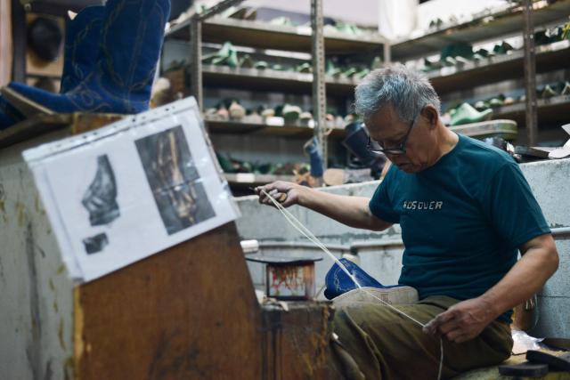 An artisan works on a pair of leather boots for the US market at the workshop of Tegep Boots, a popular Indonesian handmade leather boots maker with many dedicated customers in the United States and Europe, in Bandung, West Java on July 15, 2025. At a leather boot shop in the Indonesian city of Bandung, workers handle an order from Texas but owner Etnawati Melani says she fears such business will dwindle when US president Donald Trump's tariffs hit exports. (Photo by Timur MATAHARI / AFP) / TO GO WITH AFP STORY: Indonesia-economy-trade-US, by Yuli Krisna
