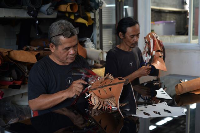 Artisans work on a pair of leather boots at the workshop of Tegep Boots, a popular Indonesian handmade leather boots maker with many dedicated customers in the United States and Europe, in Bandung, West Java on July 15, 2025. At a leather boot shop in the Indonesian city of Bandung, workers handle an order from Texas but owner Etnawati Melani says she fears such business will dwindle when US president Donald Trump's tariffs hit exports. (Photo by Timur MATAHARI / AFP) / TO GO WITH AFP STORY: Indonesia-economy-trade-US, by Yuli Krisna